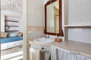 Ein Badezimmer mit weißem Waschbecken, Spiegel und gefliesten Wänden.