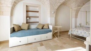 A bedroom with a built-in sofa bed, a small table, and a four-poster bed. - 3189 Dimora Bellargo by Barbarhouse (Martina Franca)