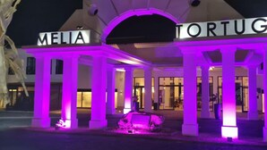 L’entrée d’un hôtel, avec les enseignes « MELIA » et « TORTUGA », présente un style architectural classique avec des colonnes et un porche.