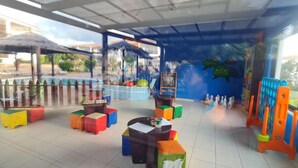 Un espace de jeux pour enfants avec des tabourets colorés, une table et une piste de bowling.