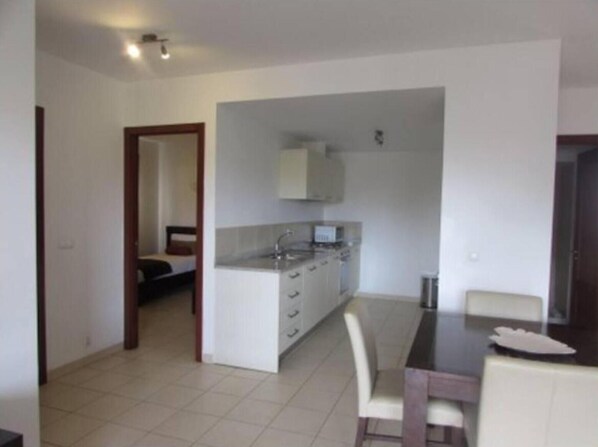 A compact kitchen with a dining area, white cabinets, and a small table.