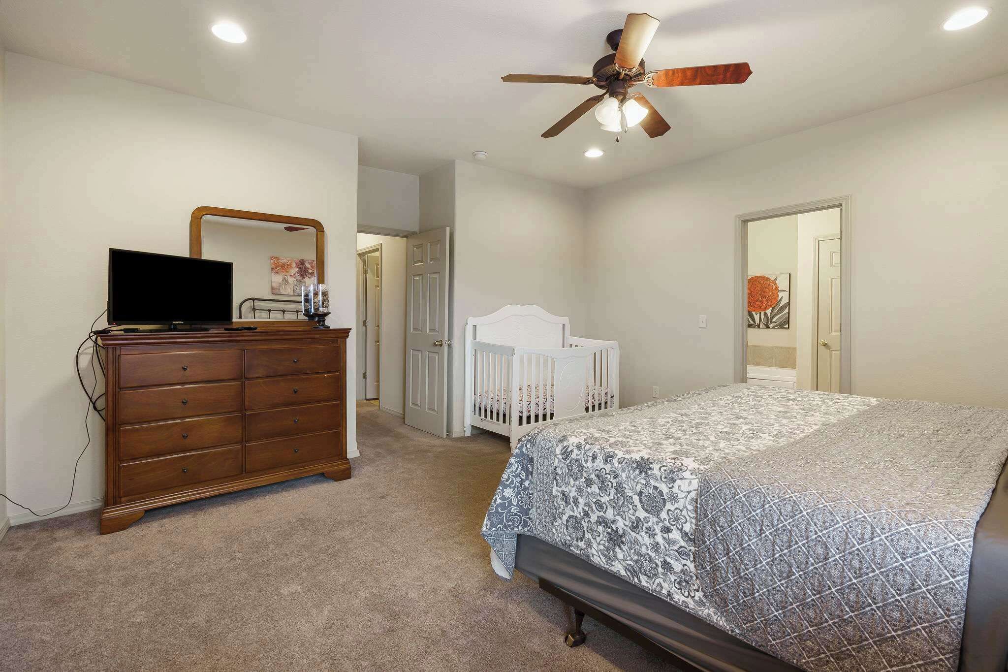 Une chambre à coucher avec un lit, une commode et un ventilateur de plafond.
