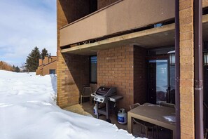 A covered outdoor area with a barbecue grill, a table, and a chair. - Tobelmann's Top Newly Remodeled (Park City)
