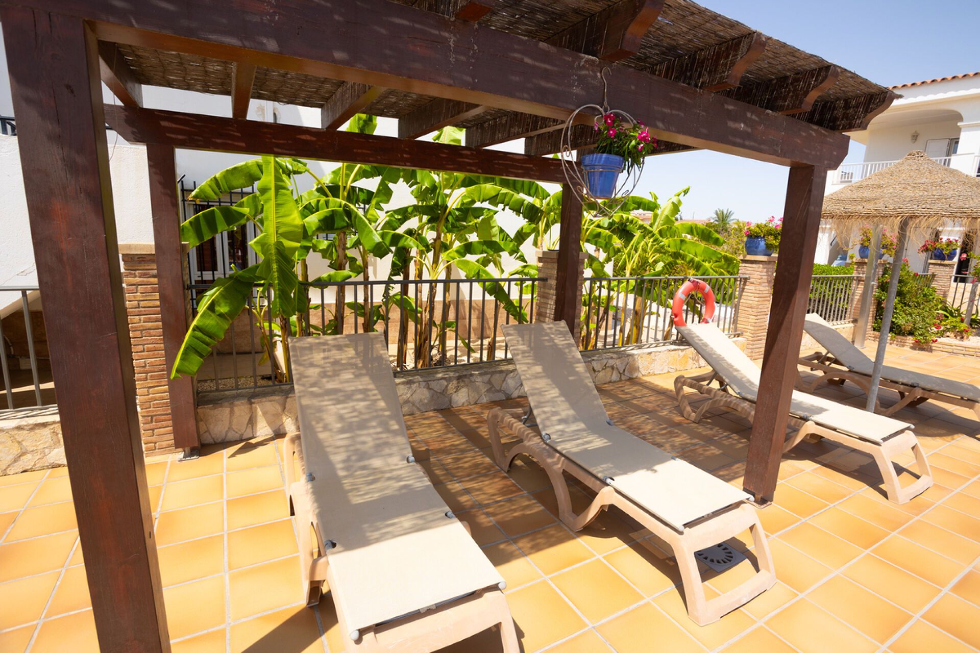 A covered outdoor seating area with lounge chairs and a pergola structure.