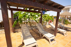 A covered outdoor seating area with lounge chairs and a pergola structure.