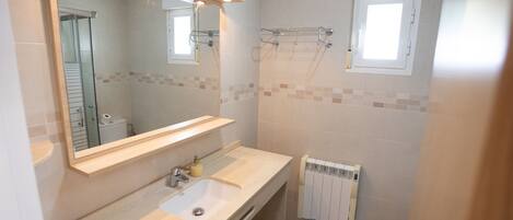A bathroom with a sink, mirror, towel rack, and a window.