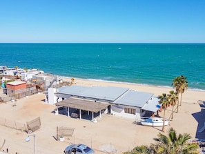 Um imóvel à beira-mar com várias casas móveis, um edifício com telhado plano e um barco na areia.
