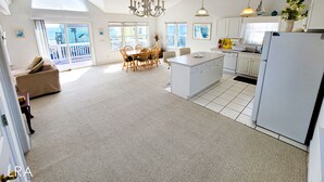 A spacious kitchen with a central island, white cabinetry, and a large window overlooking a balcony.