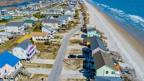 A coastal residential area with houses along the beach, a clear sky, and a view of the ocean.