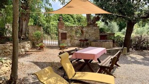 Un'area patio con tavolo e sedie, un muro in pietra e un cancello.