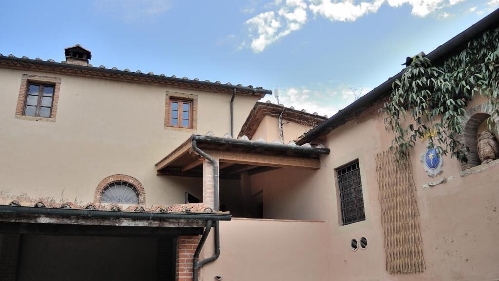 A building with a tiled roof, a brick chimney, and a small window.