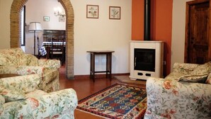 Un soggiorno con divani a motivi floreali, un tappeto decorato, un camino e una porta in legno.