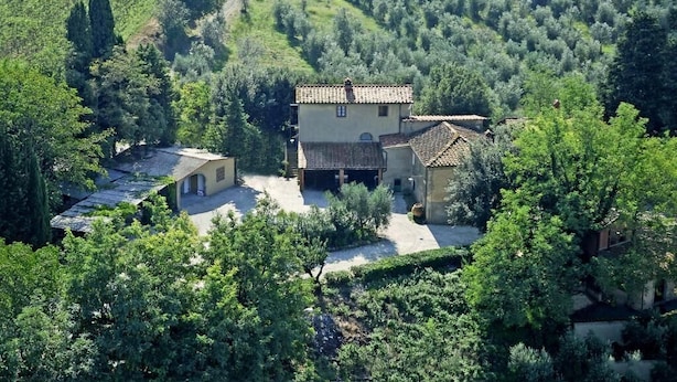 Una proprietà rurale con una casa principale e un edificio più piccolo, immersa nel verde e circondata da ulivi.