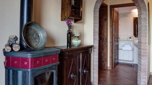 A traditional kitchen with a wood-burning stove, a cabinet with glass doors, and an arched doorway leading to another room. - The Olive  4+2 (Montescudaio)