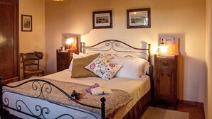 A bedroom with a bed, bedside tables, a chair, and a hanging light fixture. - The Olive  4+2 (Montescudaio)