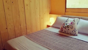 A wooden paneled room with a bed, a nightstand, and a lamp. - Lodge tent Fiordaliso 5 p. - Glamping, Nature, Tuscany 9 km from the sea (Montescudaio)