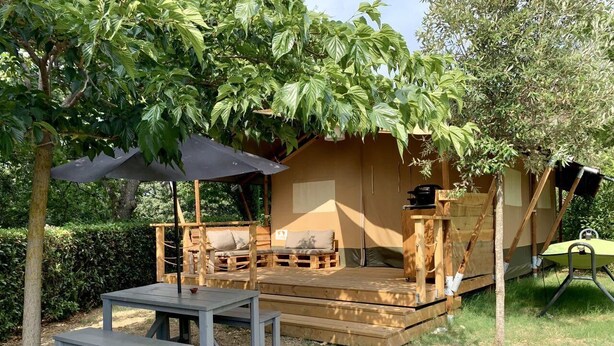 A wooden deck with a table and benches, a covered seating area, and a small structure with a chimney. - Lodge tent Fiordaliso 5 p. - Glamping, Nature, Tuscany 9 km from the sea (Montescudaio)