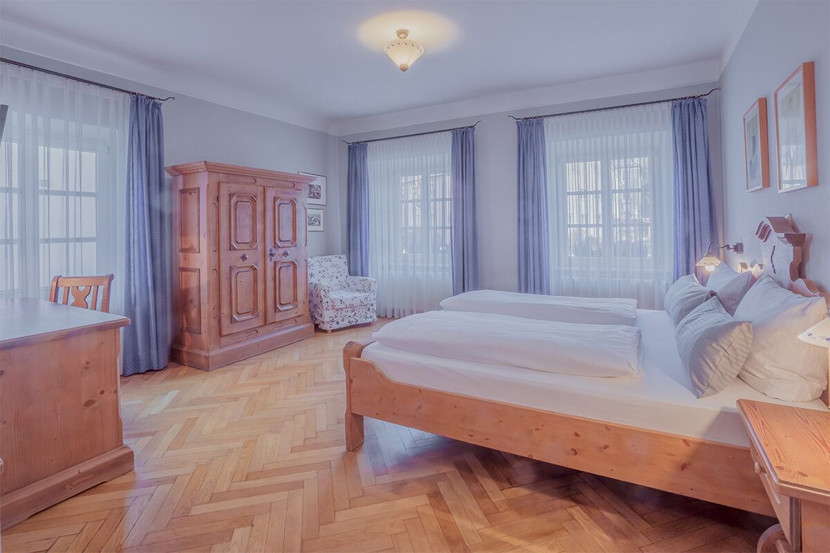 Un dormitorio con una cama y un armario de madera, una silla y un escritorio.