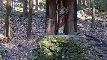 Una estructura de madera rústica con una estatua en su interior, rodeada de un bosque.