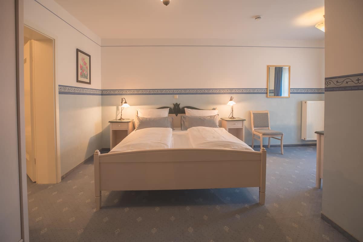 Ein Hotelzimmer mit einem Einzelbett, Nachttischen, einem Sessel, einem Spiegel und einer Heizung.