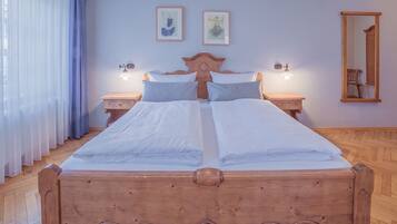 Uma cama de casal com cabeceira de madeira, duas mesas de cabeceira com luminárias e uma obra de arte na parede.