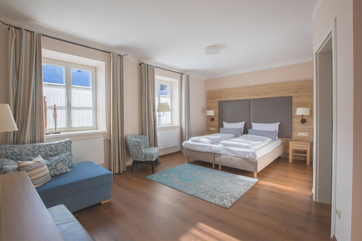 Ein modernes Schlafzimmer mit einem Bett, einer Couch, einem Sessel und einem Fenster.