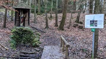 A forested area with a wooden structure, a wooden bridge, and a signpost.