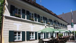A building with outdoor seating and green awnings. - Brauereigasthof & Hotel Maierbräu (Altomunster)