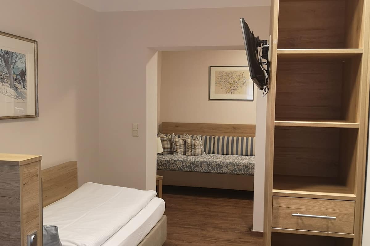 Ein Schlafzimmer mit einem hölzernen Bett, einem Nachttisch, einem Kleiderschrank und einem an der Wand befestigten Fernseher.