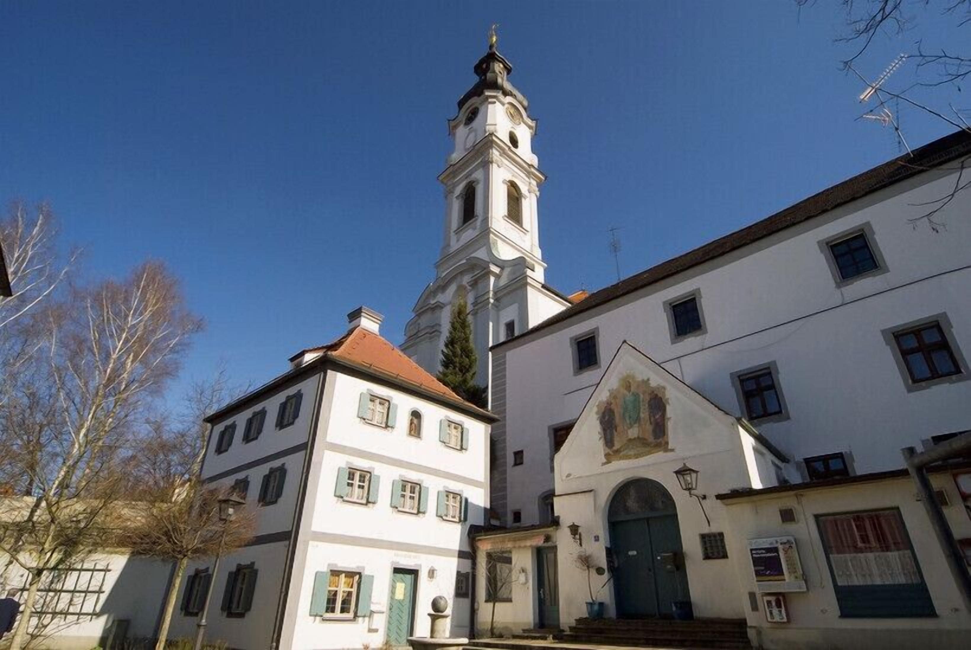 Un bâtiment historique doté d’un imposant clocher, d’une façade traditionnelle et d’une petite entrée avec une porte et quelques marches.