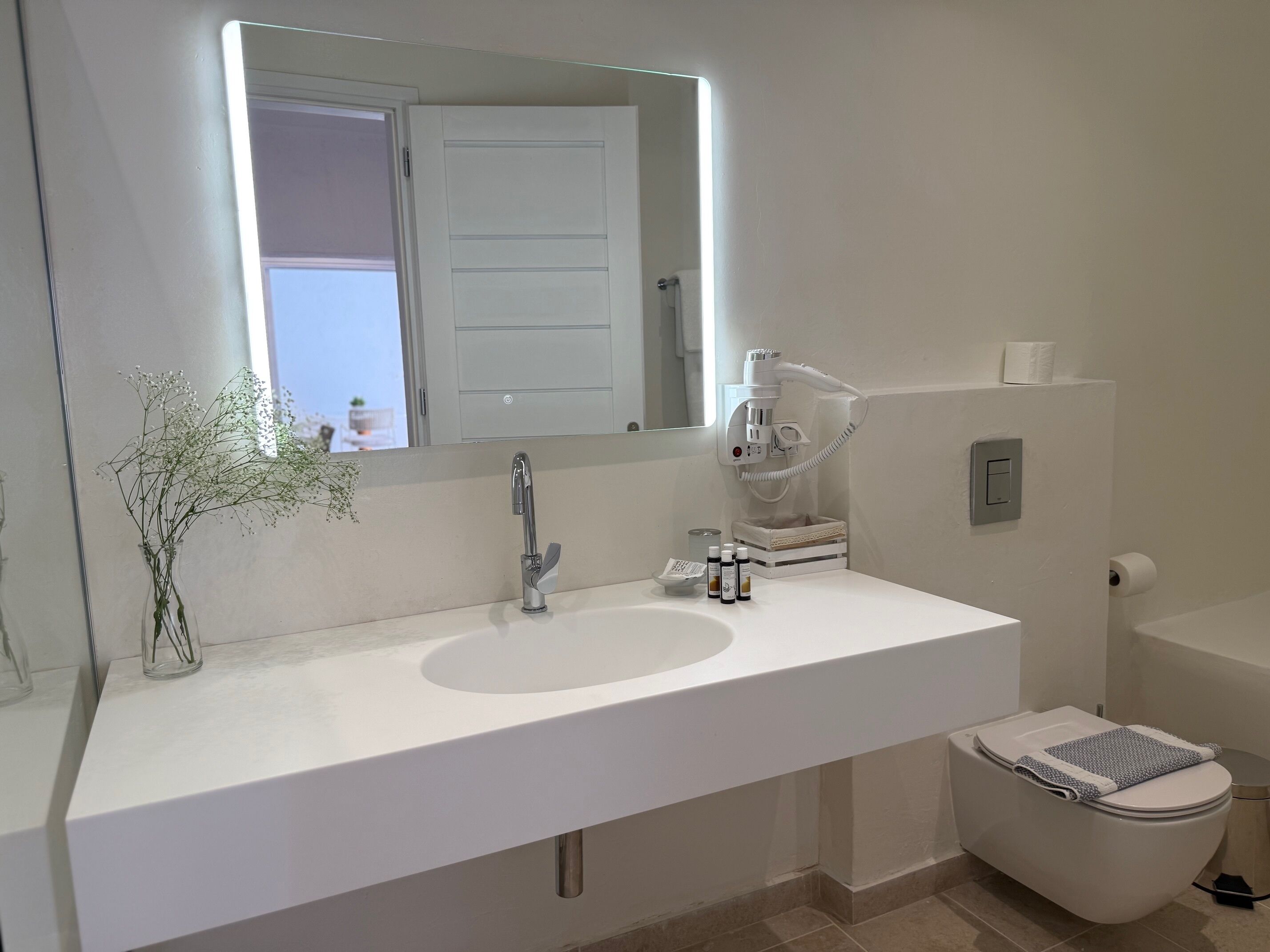 A bathroom with a white sink, a mirror, a toilet, and a shower.