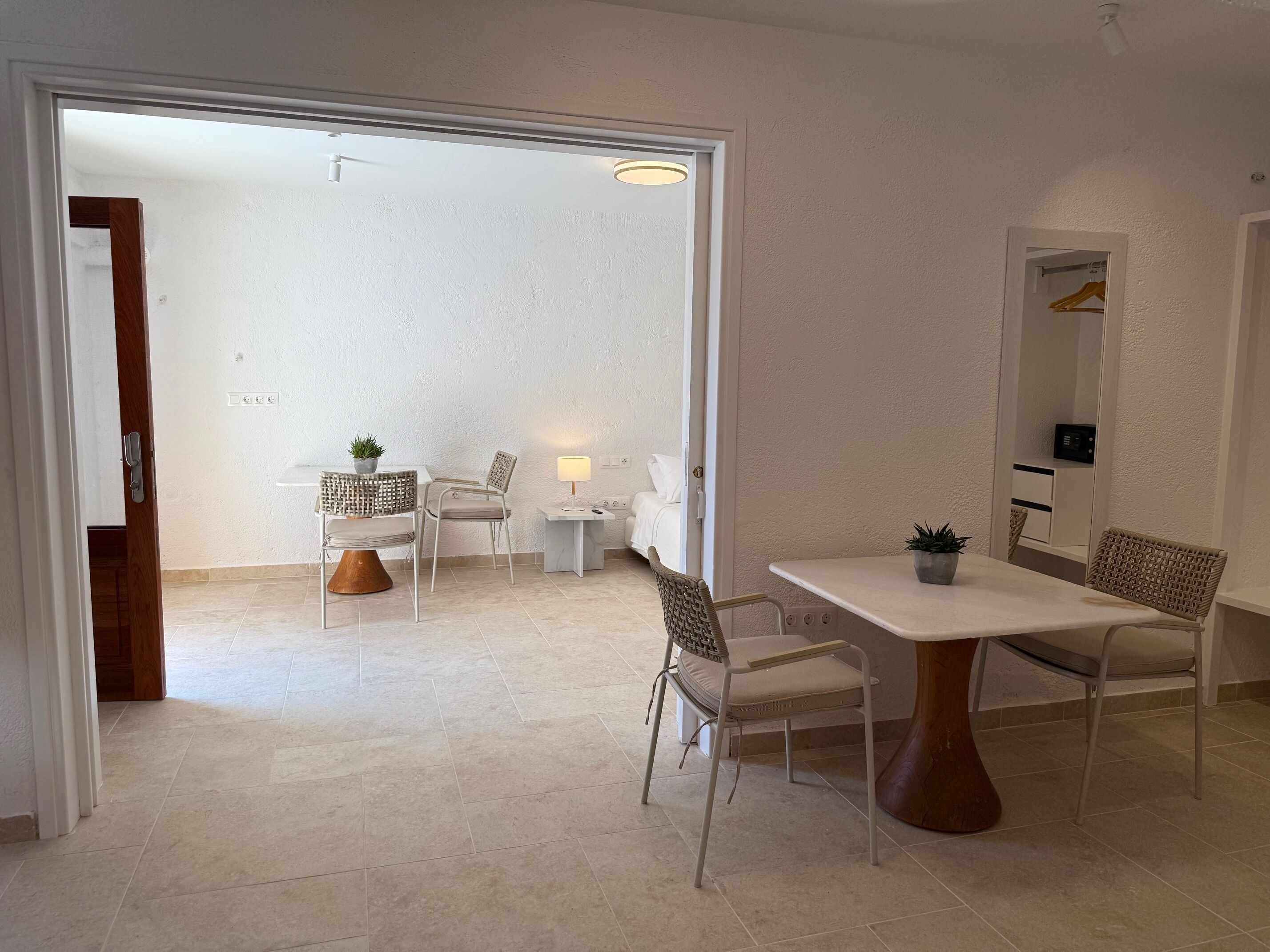 A modern, open-plan living space with a dining area, seating, and a view into another room.