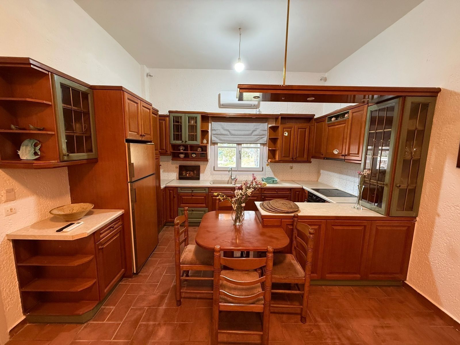 A compact kitchen with wooden cabinets, a central island, and a window.