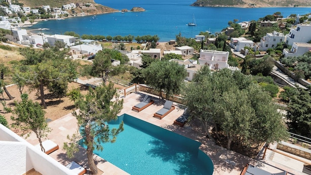 A pool area with lounge chairs and a view of the sea.