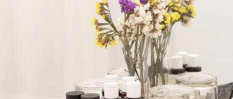 A tray with essential oils and a vase of flowers on a white countertop.