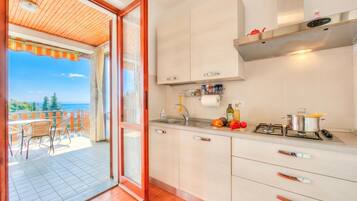 Una cucina con vista su un balcone, completa di fornelli e pensili.