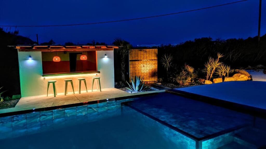 A poolside bar with stools, a small pool, and a tiled wall.