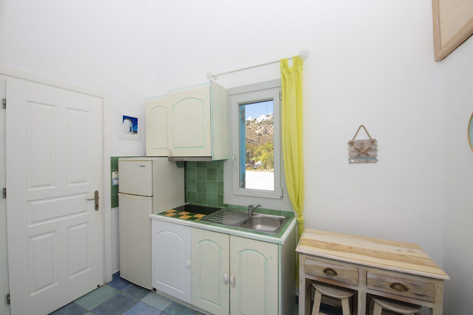 A compact kitchen with a window, a sink, and a small wooden table.