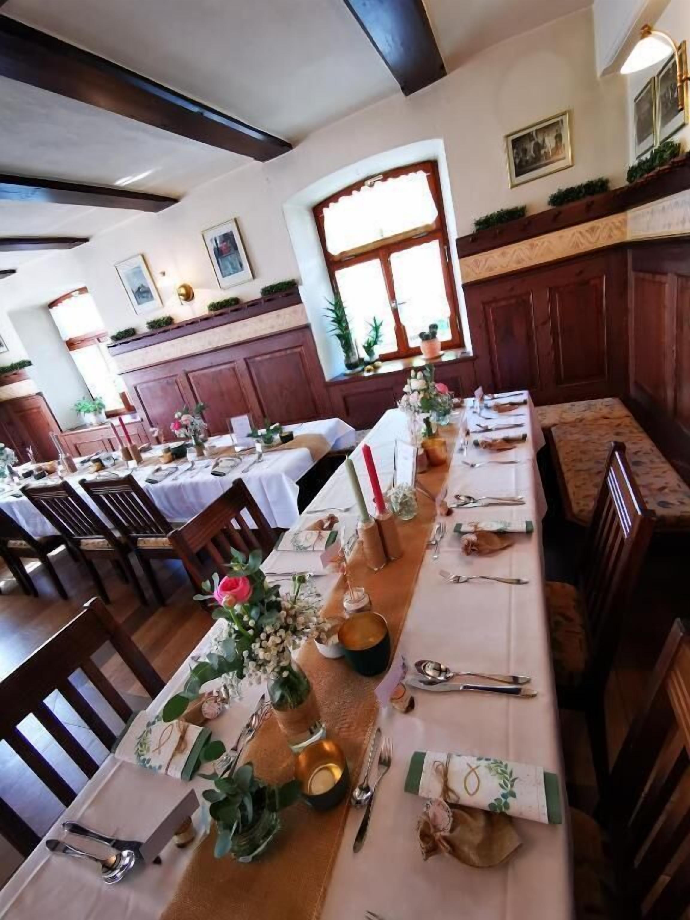 Un restaurant avec de longues tables dressées pour le repas, agrémentées de compositions florales et de couverts disposés avec soin.