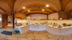 A spacious kitchen with a curved island, wooden ceiling, and stone flooring. - Landgasthof Büttel (Strullendorf)