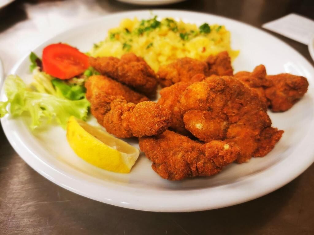 A plate with fried chicken, mashed potatoes, a slice of lemon, and a side salad.