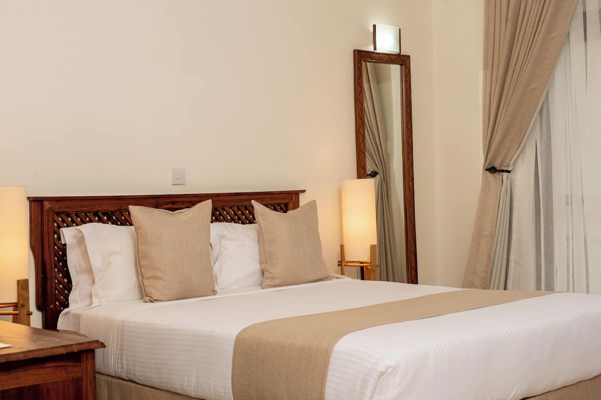 A neatly made bed with a wooden headboard, two bedside lamps, and a mirror on the wall.