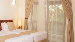 A hotel room with two beds, a wooden headboard, a bedside table with a lamp, and sheer curtains. - Forest Hill Hotel (Arusha)
