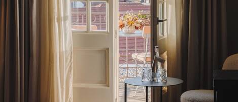 A room with a wooden floor, a round table with a vase and glasses, and a chair.