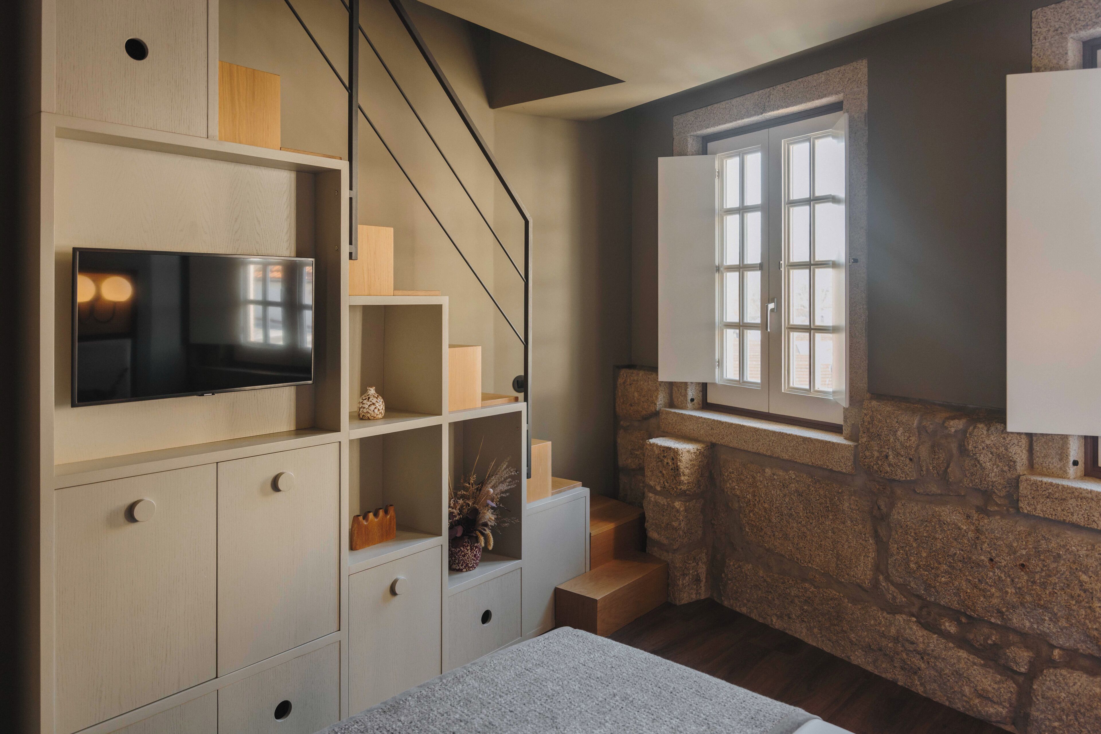 Ein modernes Zimmer mit integrierten Regalen, einem Flachbildfernseher, einer Wand aus Stein und einem Fenster mit Blick.