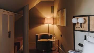 Une chambre d’hôtel équipée d’un lit, d’un bureau, d’une chaise, d’une lampe et d’un luminaire fixé au mur.