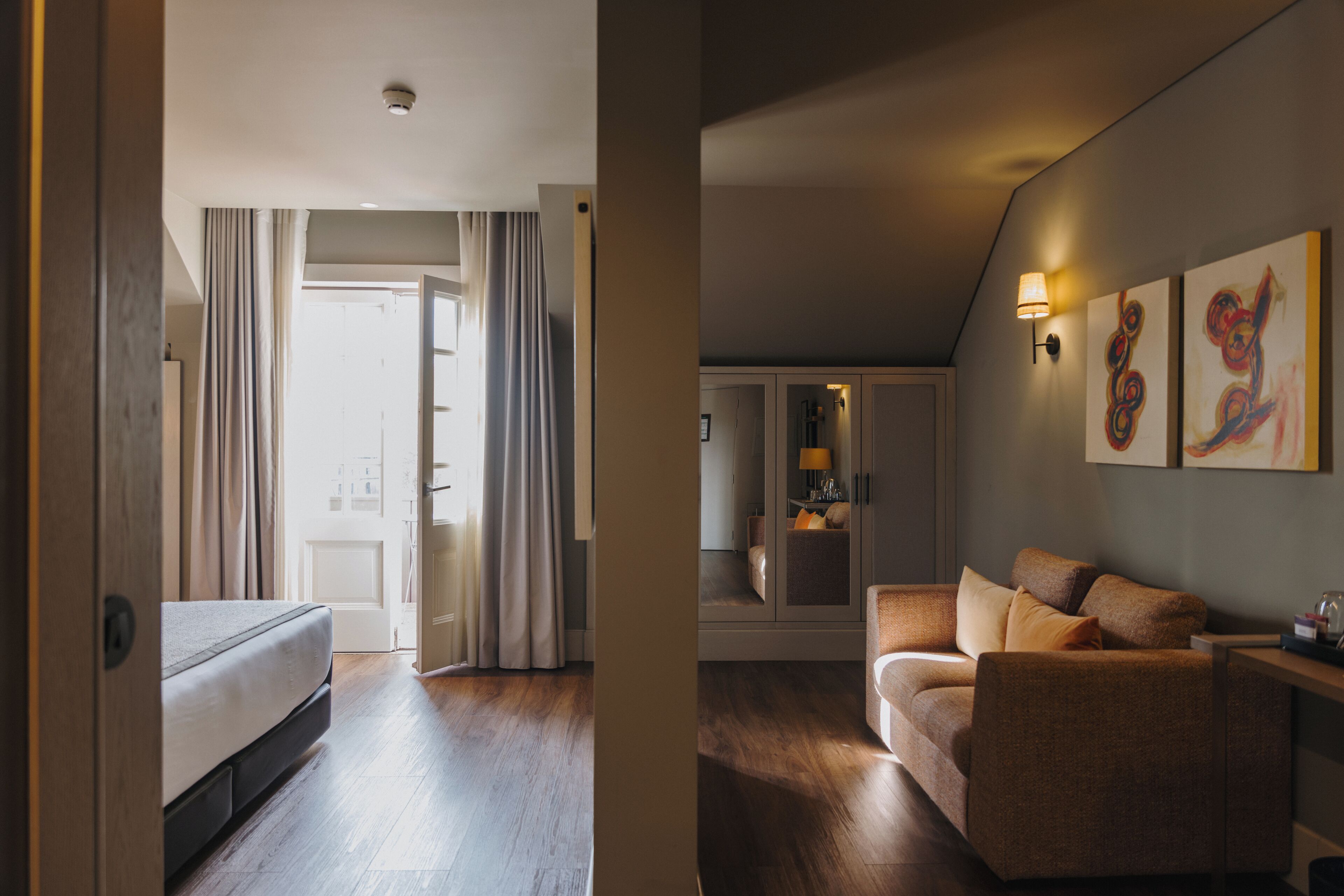 Une chambre d’hôtel avec un lit, un canapé, une armoire et des œuvres d’art accrochées au mur.