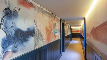 A hallway with abstract wall art and a number '302' on the wall.