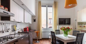 A modern kitchen with a dining area, featuring a stove, sink, and a dining table with chairs. - Montegrappa Apartment by Wonderful Italy (Bologna)