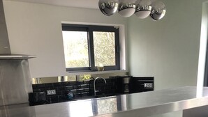 A modern kitchen with a stainless steel countertop, a built-in sink, and a window above the sink. - Modern country house with spacious rooms and swimming pool (Doingt)
